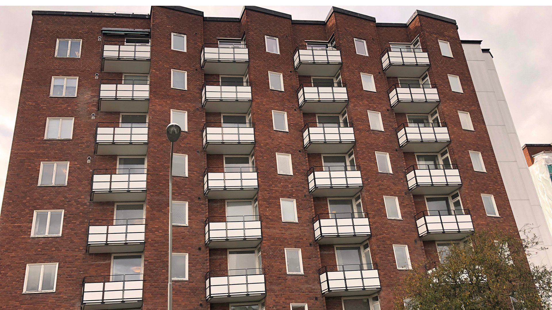 Fasad i röd tegel med vita balkonger i Lisberg, där Ebab anlitades för att renovera dessa. 