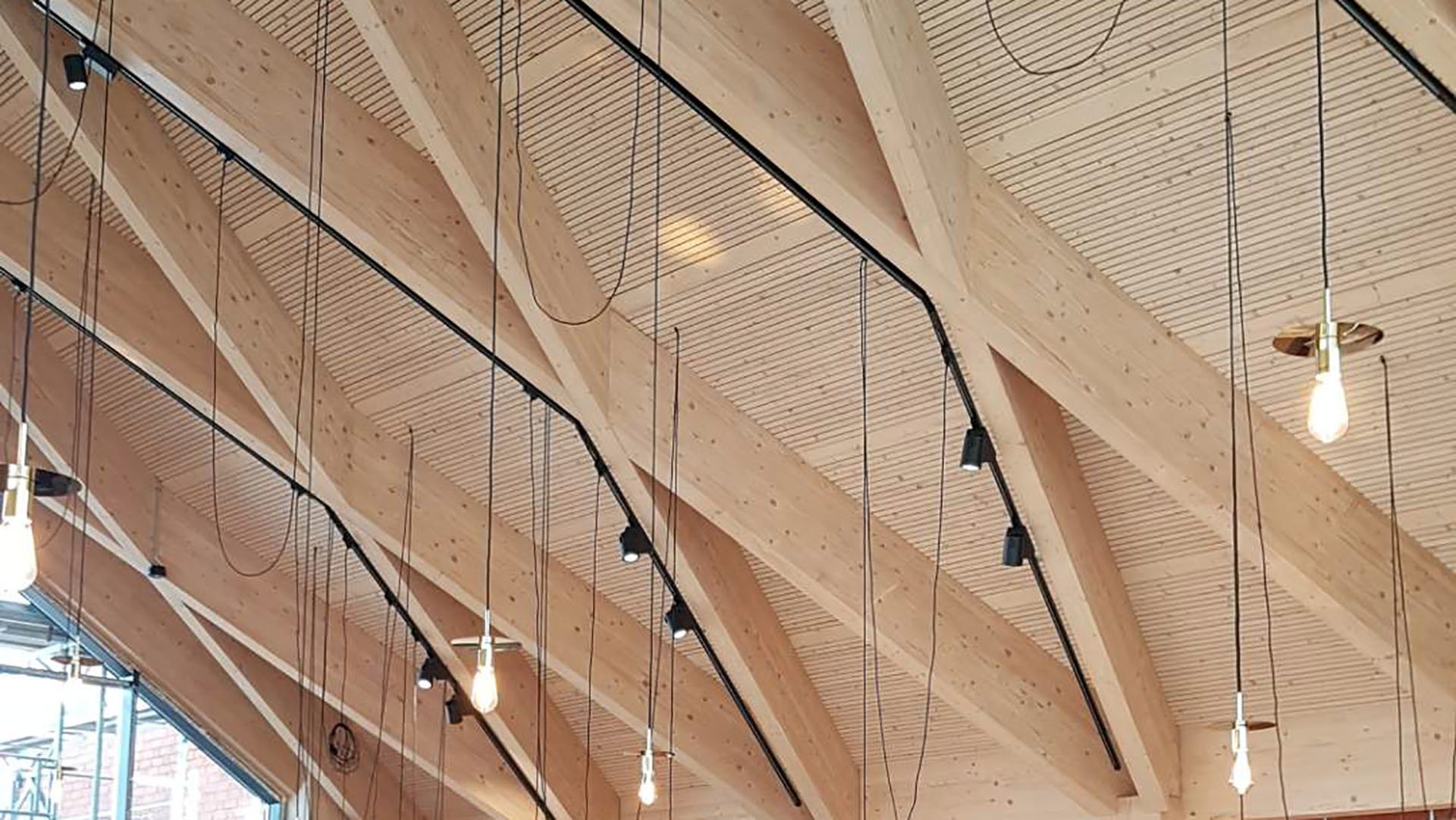 Innertak i trä med hängande glödlampor och svarta armaturer i Storkök Magnolia där Ebab medverkat från förstudie till bygghandling i omfattande renovering