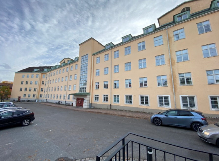 Fasaden till Stureby sjukhem med puts i ljusbeige och grönt tak där förstudie samt renovering av fönster genomförts